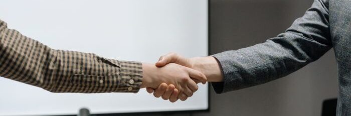 Two business professionals shaking hands in a modern meeting room, symbolizing successful collaboration.